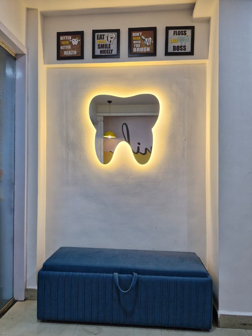 Tooth-shaped illuminated mirror and blue bench in the waiting area